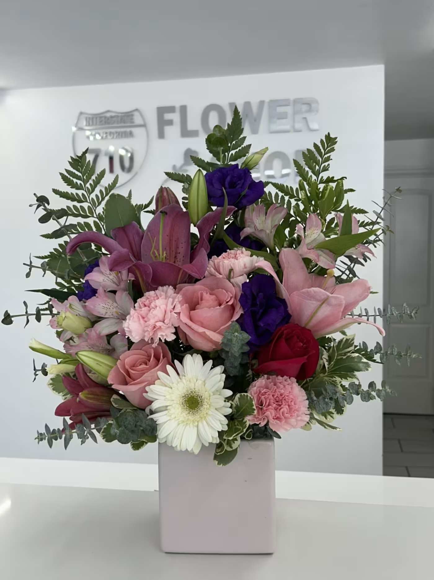 Blossoms In Harmony - Mixture of lilies, roses, carnations, lisianthus, and daisies create a vibrant yet balanced arrangement that feels joyful and elegant! (If some flowers and/or the vase are not available there will be minor substitutions.)
