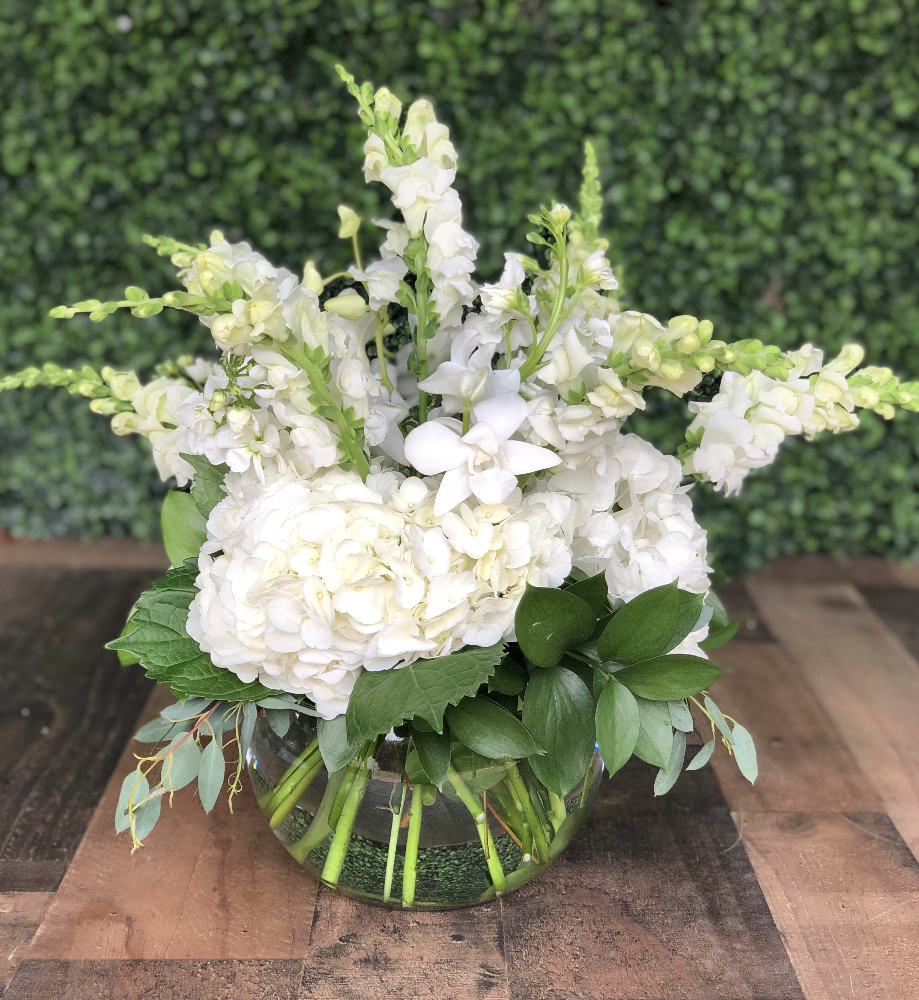 WHITE BUBBLES - Assorted white flowers including hydrangeas, orchids, stock and snap dragons with greens in a bubble bowl.