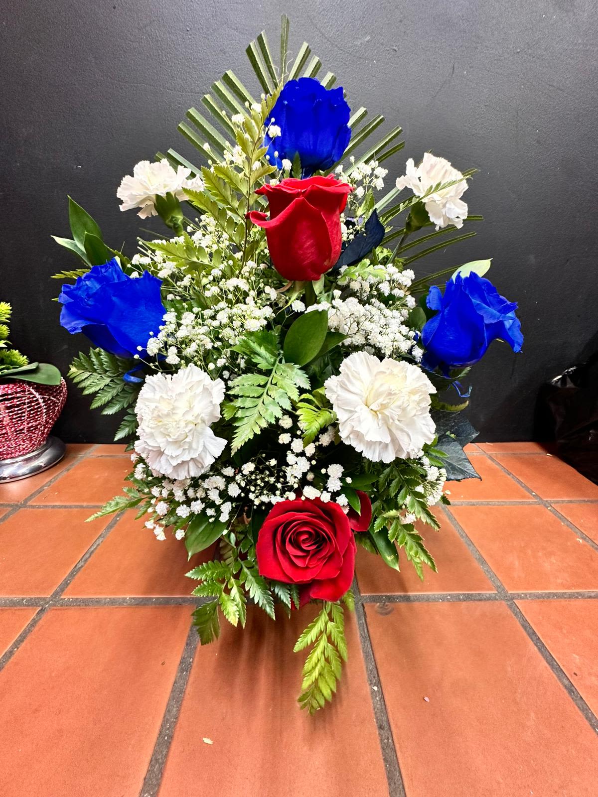 Red, blue, and white rose and carnation event arrangement in a fan-shaped design