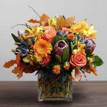 Peach Lasting Arrangement - A vibrant autumn-inspired floral arrangement featuring warm shades of orange, golden yellow, and soft peach.