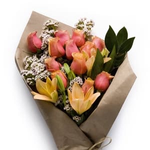 Bouquet of pink roses and peach lilies with white filler flowers wrapped in brown paper