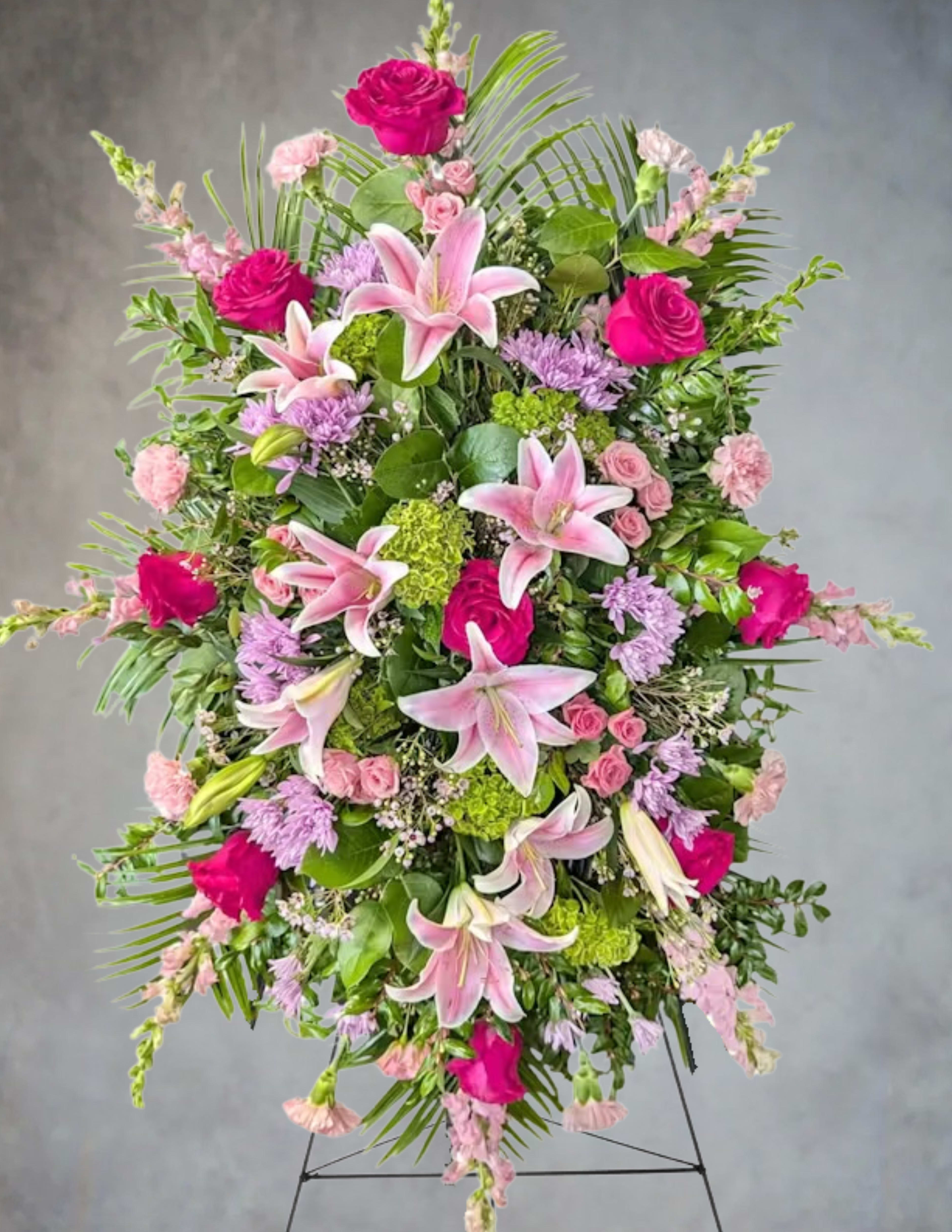 Tall pink and green standing spray with lilies and roses on a metal easel