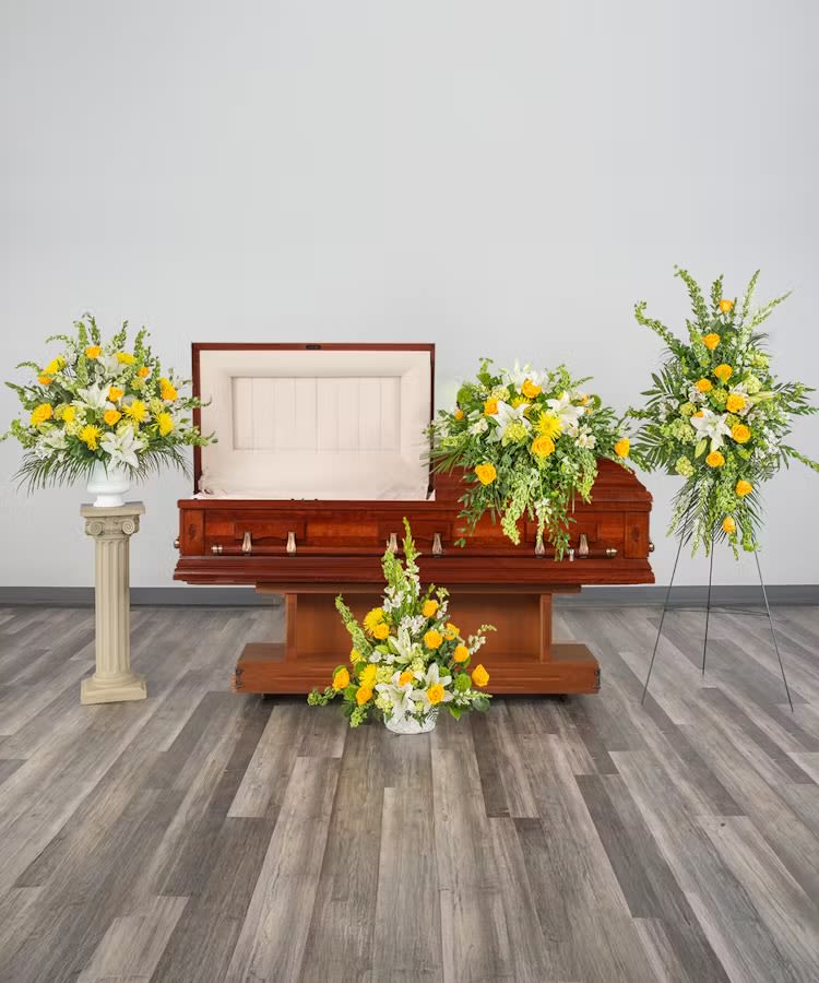 Set of yellow and white funeral floral arrangements around an open wooden casket