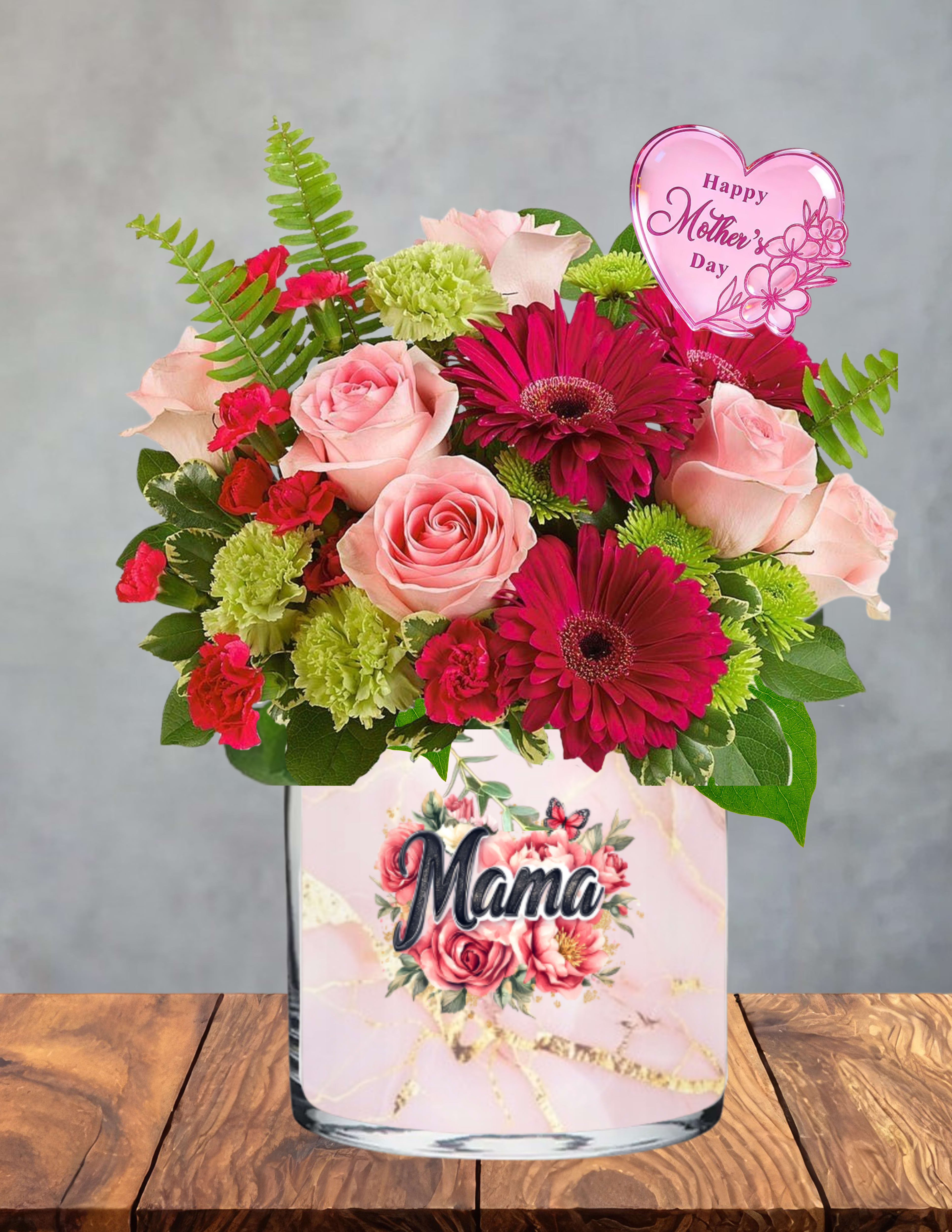 Forever my mama - A vibrant celebration of the woman whose love shapes everything.  Forever My Mama bursts with bright pink roses, radiant red gerberas, and lush green blooms, creating a joyful, energetic mix that feels just like her — strong, loving, and full of life. Soft greenery and ferns add natural movement, while the pink heart pick brings a sweet Mother’s Day touch that makes the whole design feel personal and full of affection.  Presented in a charming “Mama” vase adorned with roses and a fluttering butterfly, this arrangement is a beautiful reminder of the bond that lasts a lifetime. It’s bold, heartfelt, and overflowing with gratitude — the perfect way to honor the mama who means the world.