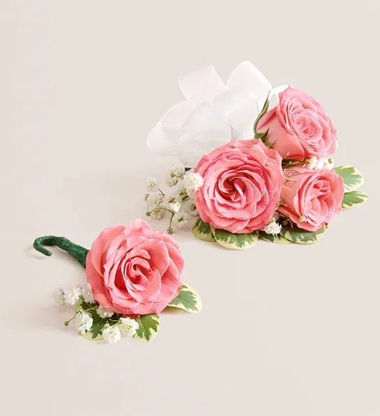 Pink Spray Rose Corsage and Boutonniere (White) - NEW Make a special occasion even more memorable with our hand-designed corsage and boutonniere pairing. Each is made with carefully chosen pink spray roses complemented with baby’s-breath and greenery. The corsage, which can be worn on the wrist or pinned to clothing, comes with ribbon in your choice of seven colors: black, gold, light blue, light pink, purple, silver, or white.