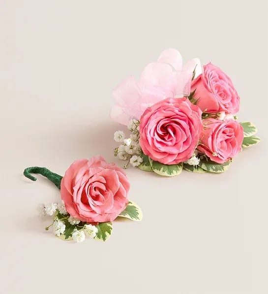 Pink Spray Rose Corsage and Boutonniere (Pink) - NEW Make a special occasion even more memorable with our hand-designed corsage and boutonniere pairing. Each is made with carefully chosen pink spray roses complemented with baby’s-breath and greenery. The corsage, which can be worn on the wrist or pinned to clothing, comes with ribbon in your choice of seven colors: black, gold, light blue, light pink, purple, silver, or white.