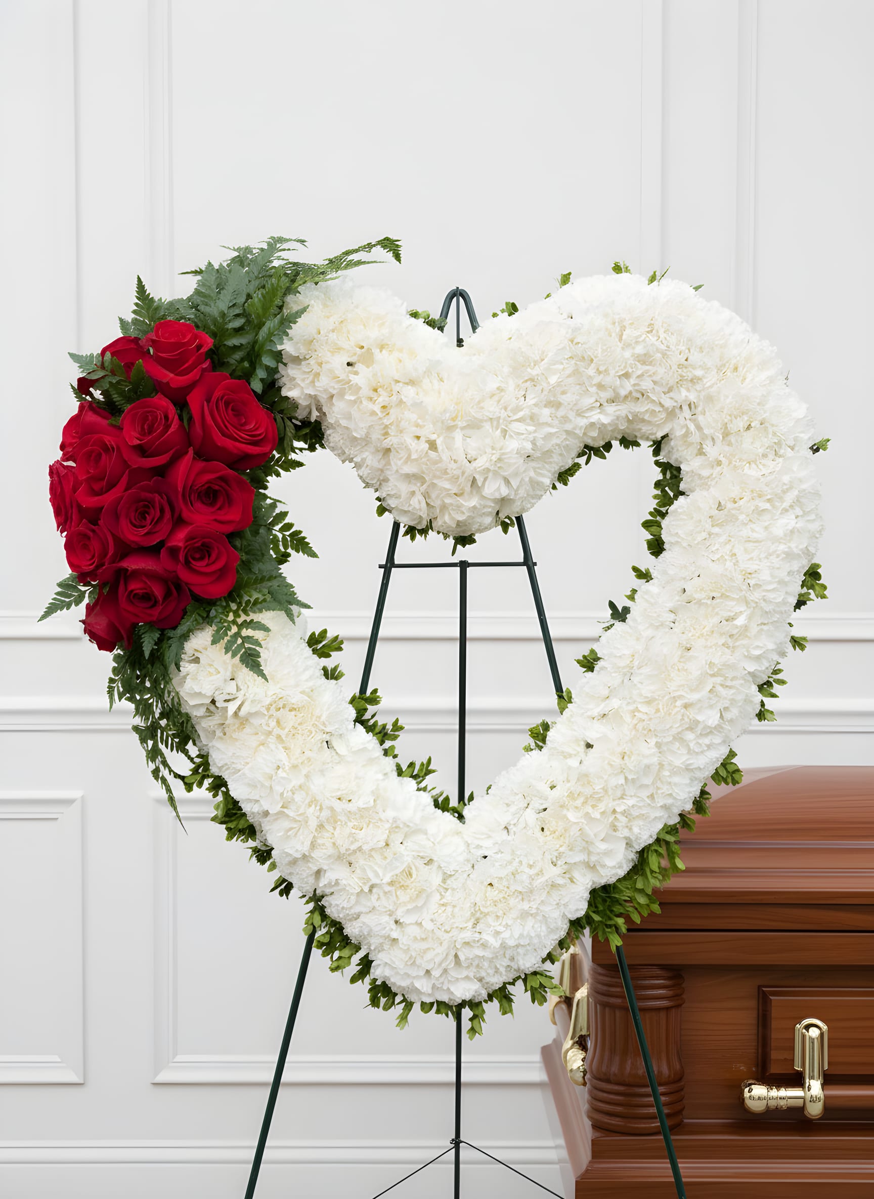 Forever in My Heart - A timeless expression of love and remembrance, this elegant heart-shaped wreath is designed to honor a life deeply cherished. Crafted with a lush base of soft white blooms and accented with a striking cluster of rich red roses, it symbolizes purity, love, and enduring devotion.  The heart shape serves as a powerful tribute, representing the everlasting bond shared with a loved one. Thoughtfully arranged with fresh greenery for added depth and texture, this piece offers a graceful and meaningful presence during moments of remembrance.  Available in multiple sizes, this arrangement stands as a beautiful and heartfelt expression of sympathy, love, and eternal connection.