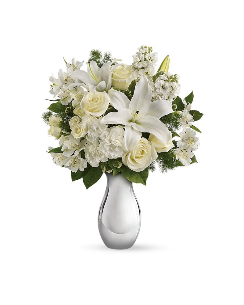 Arrangement of white lilies, roses, carnations, and other blooms in a silver vase