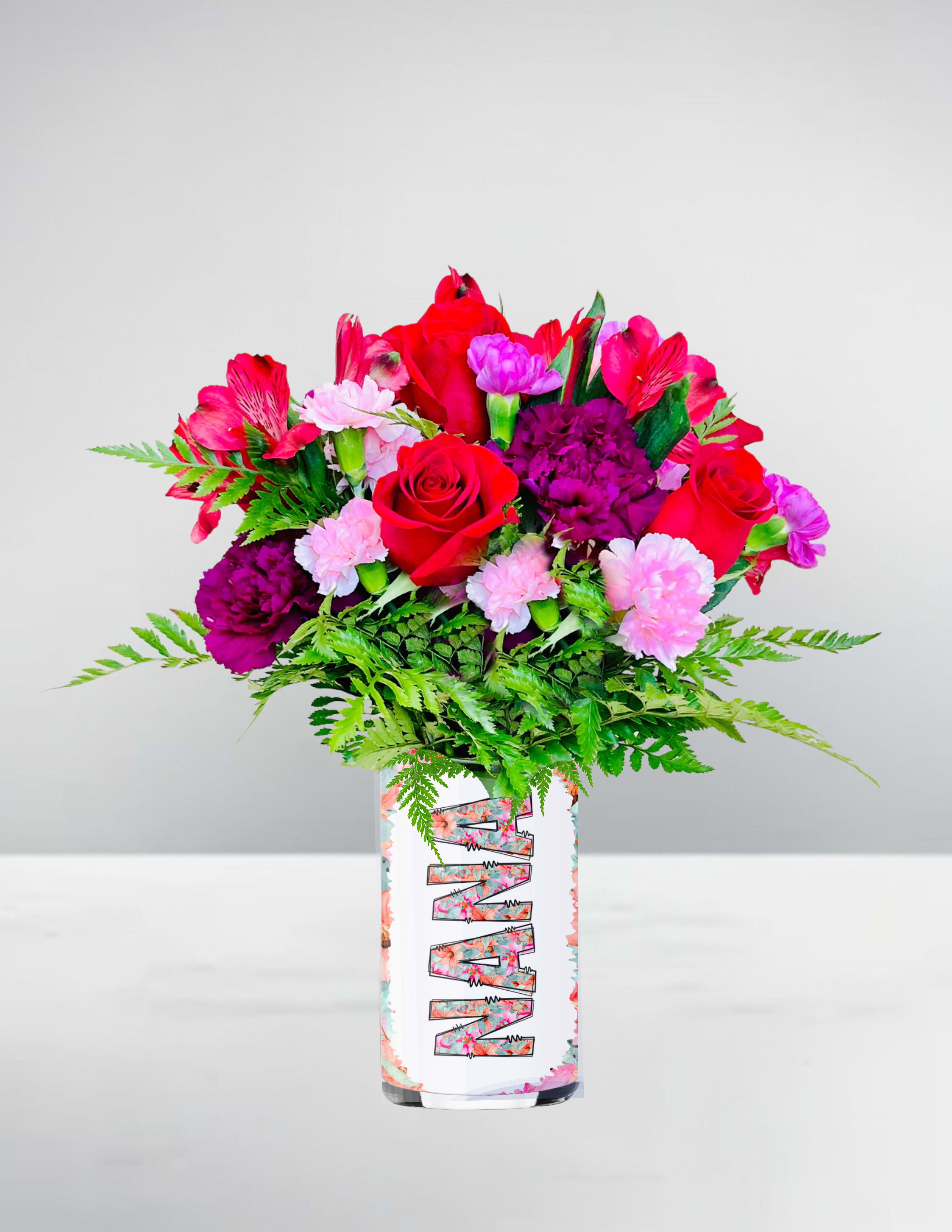 Mixed bouquet of red roses and pink blooms in a white patterned cylinder vase
