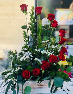Tall arrangement of red roses with white accent flowers in a white wooden box