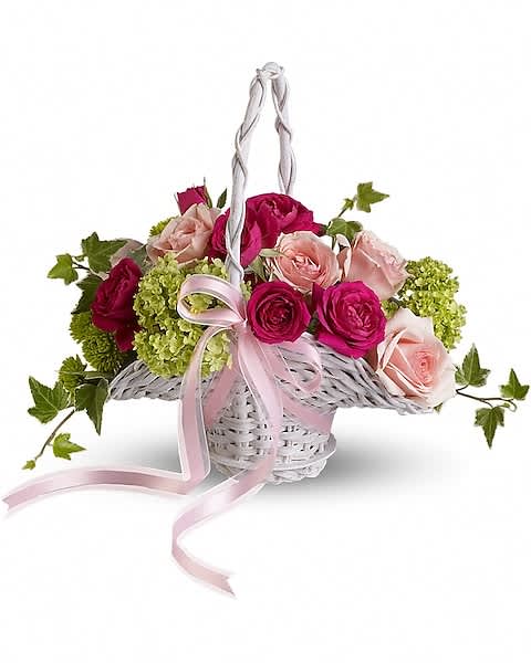 White wicker basket of hot pink and pale pink roses with green hydrangea and a pink ribbon bow