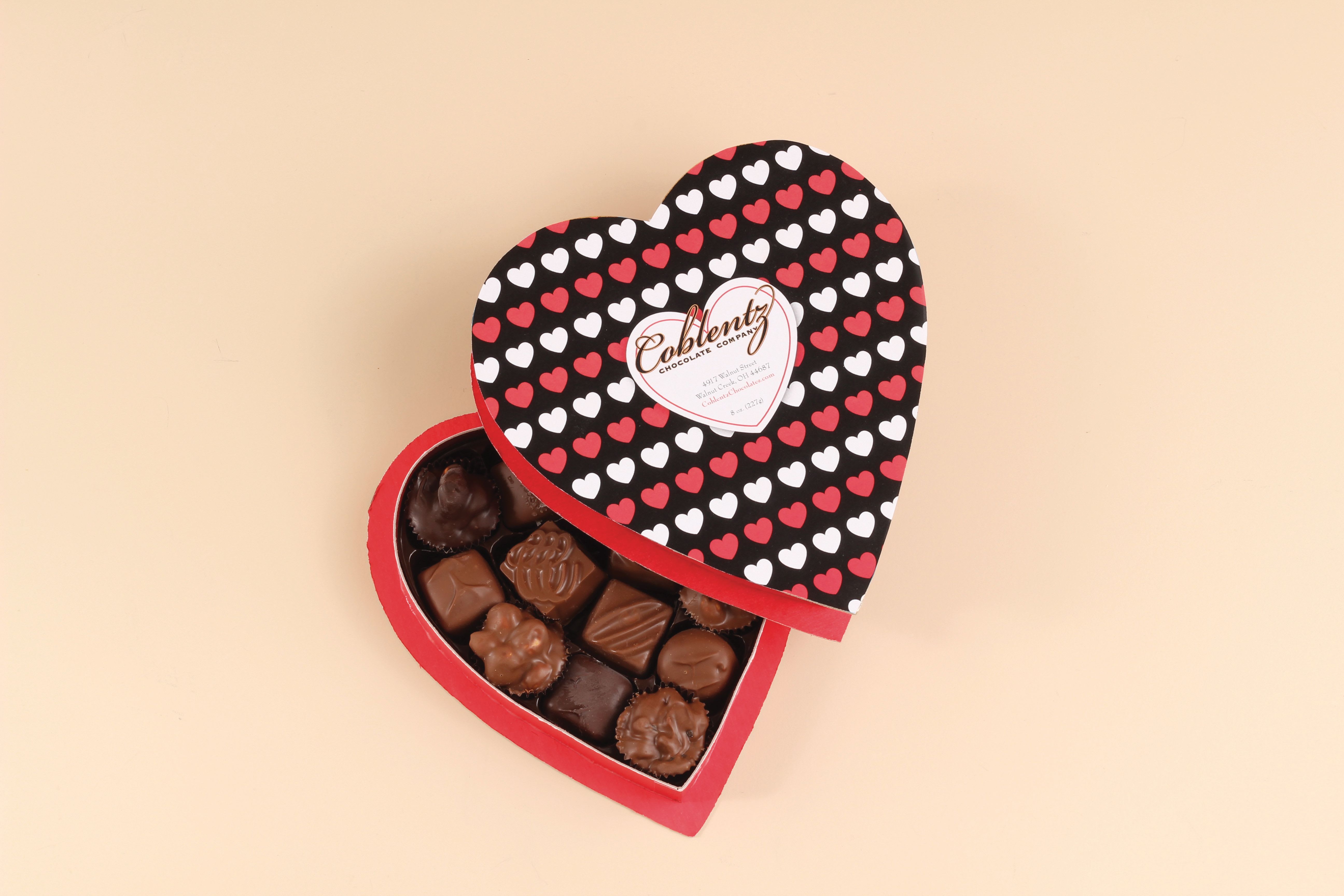 Heart-shaped box of assorted chocolates with a patterned lid of red and white hearts.