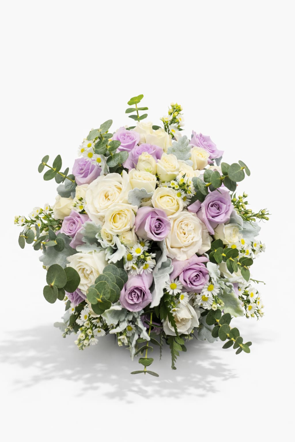 Whispers of Love Bridal Bouquet - Soft, romantic, and full of natural charm, this elegant hand-tied bouquet features delicate lavender roses paired with creamy white spray roses, airy chamomile blooms, and fresh eucalyptus greenery. Finished with a graceful satin ribbon, the design feels light, fresh, and effortlessly beautiful.  The gentle lavender tones symbolize admiration and grace, while the soft white blooms add purity and timeless elegance. Perfect for weddings, bridesmaids, anniversaries, or simply to express love in the most delicate way.  A charming garden-inspired bouquet that feels as sweet and graceful as the moment it celebrates.