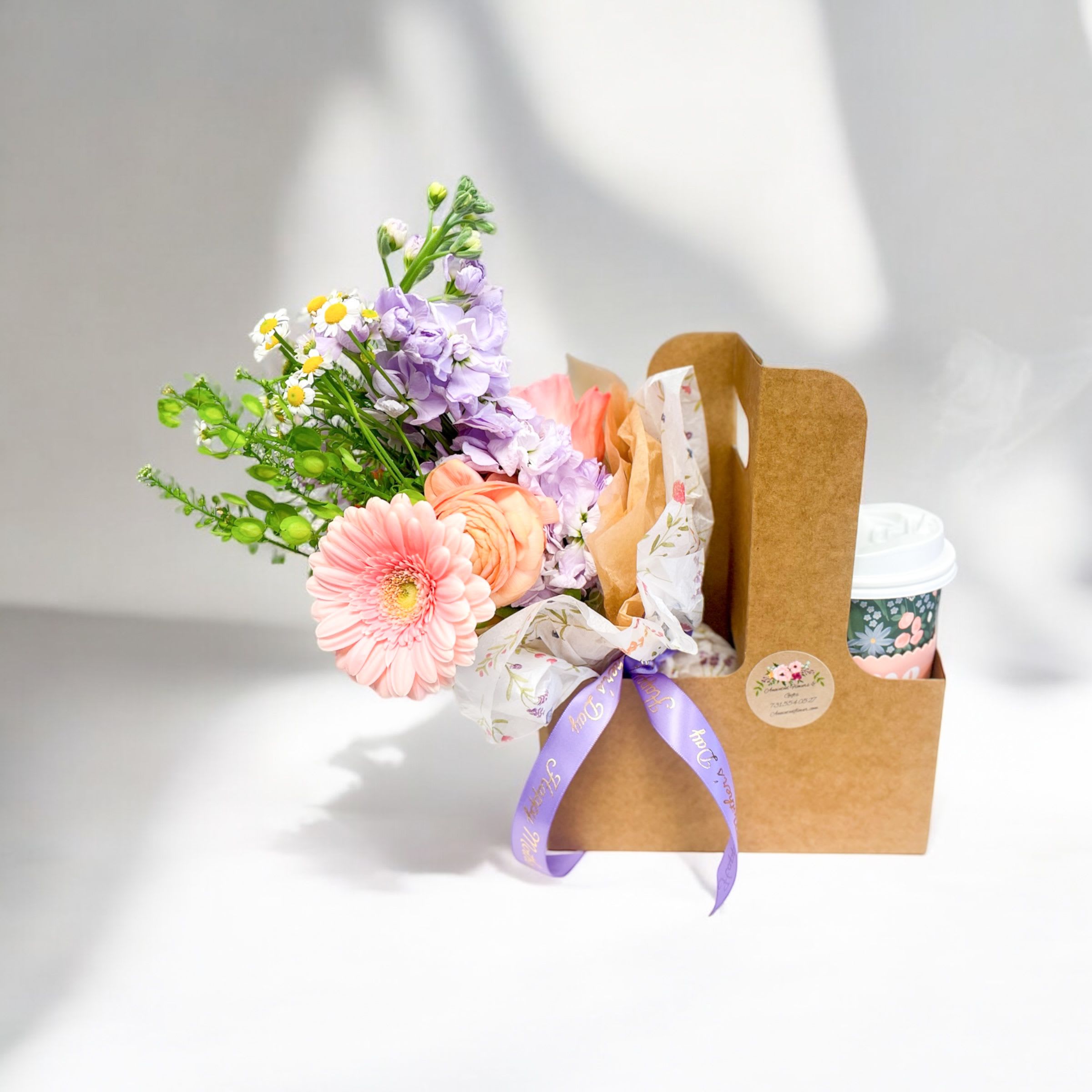 Small pastel flower bouquet and to-go cup in a brown cardboard drink carrier with ribbon