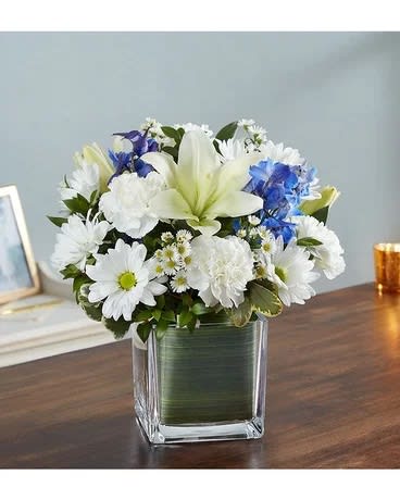 White and blue flower arrangement in a square glass vase