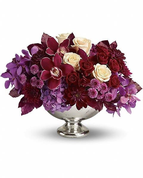 Lush and Lovely - "Lush and lovely" might seem like a bit of an understatement when gazing at this incredible arrangement of luxurious flowers delivered in a divine silver bowl. Let's add "beautiful and breathtaking" to the description. Spectacular red cymbidium orchids, purple mokara orchids, lavender hydrangea, crème roses, dark red spray roses, burgundy dahlias, purple and lavender chrysanthemums and burgundy copper beech arrive in a silver bowl.