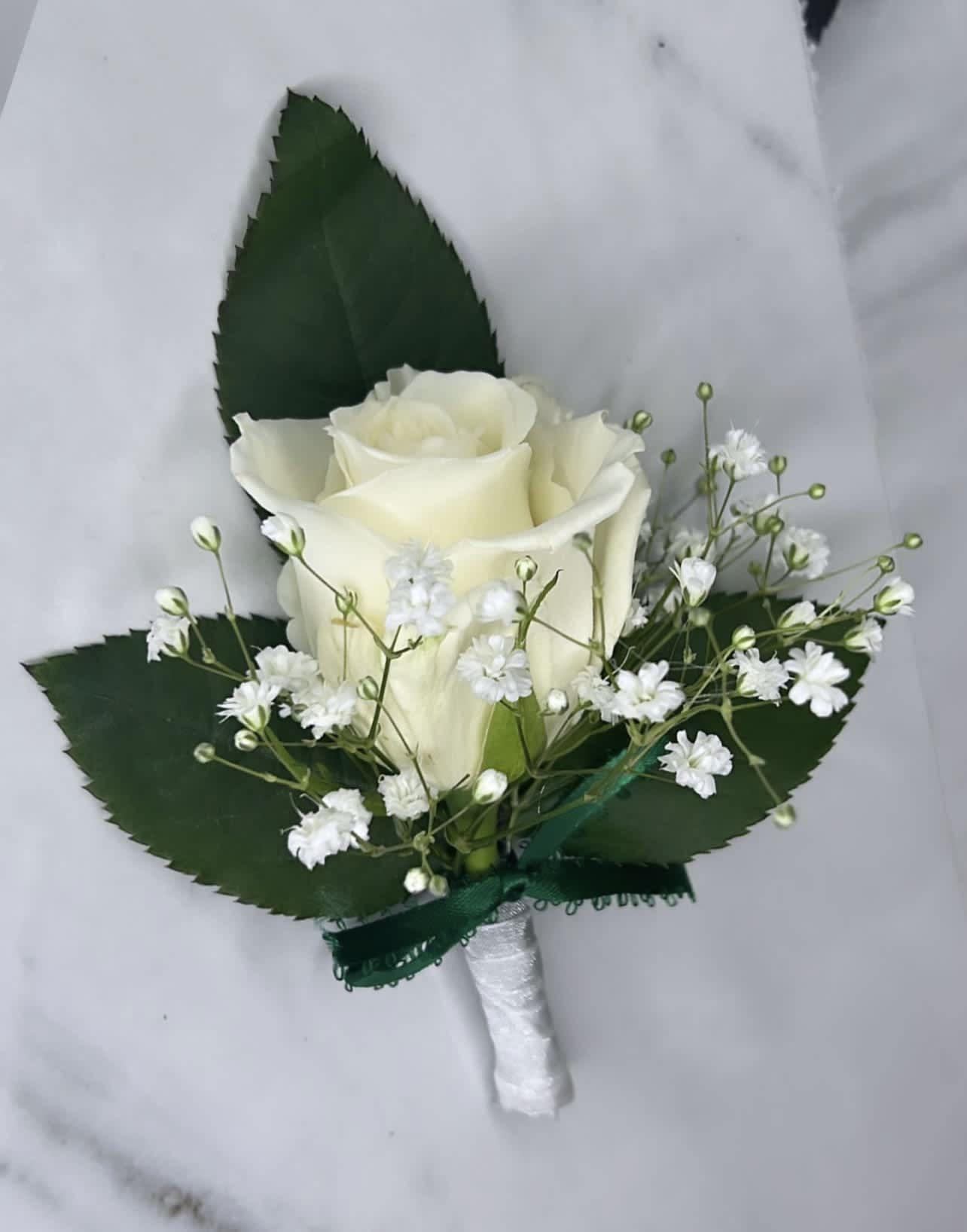 Boutonniere by Flowers N More - A classic white boutonnière that compliments any suit. A perfect addition for any prom, formal, or wedding event.   IN SPECIAL INSTRUCTION BOX YOU CAN TELL US IF YOU WANT A WHITE ROSE OR A RED ONE!