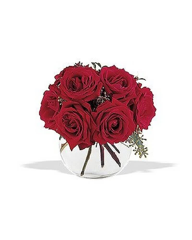 Compact arrangement of red roses in a round clear glass bowl vase