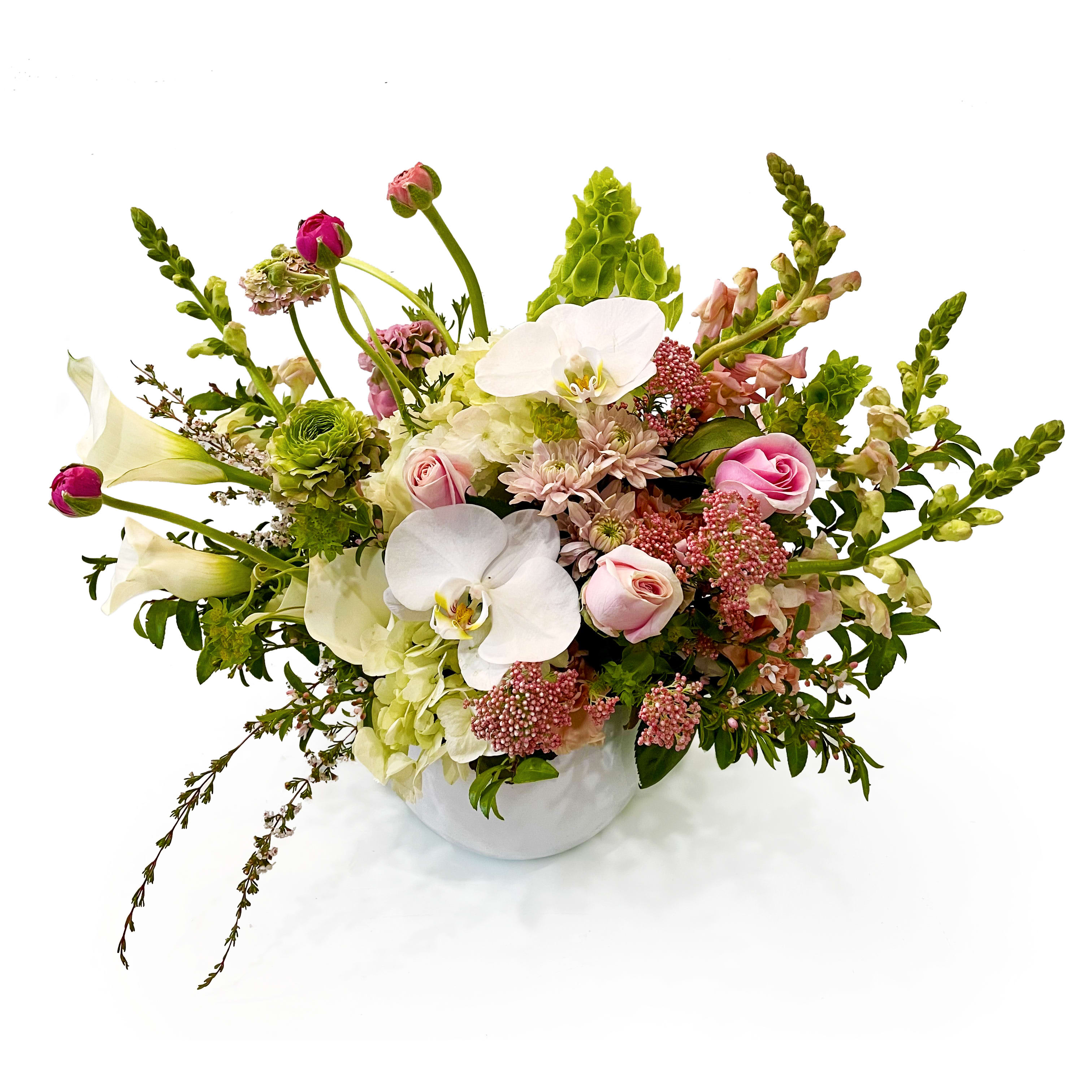 Lush arrangement of white orchids, calla lilies, and pink roses in a round white vase