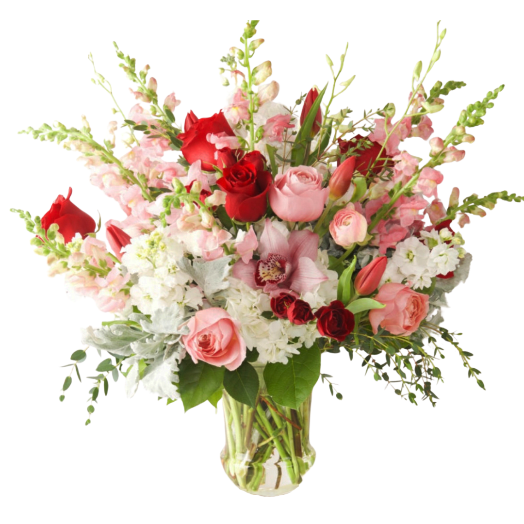 Wild Heart  - Premium roses in a mix of colors between red, and pinks sitting in a mix of airy greens, arranged in a tall vase.   