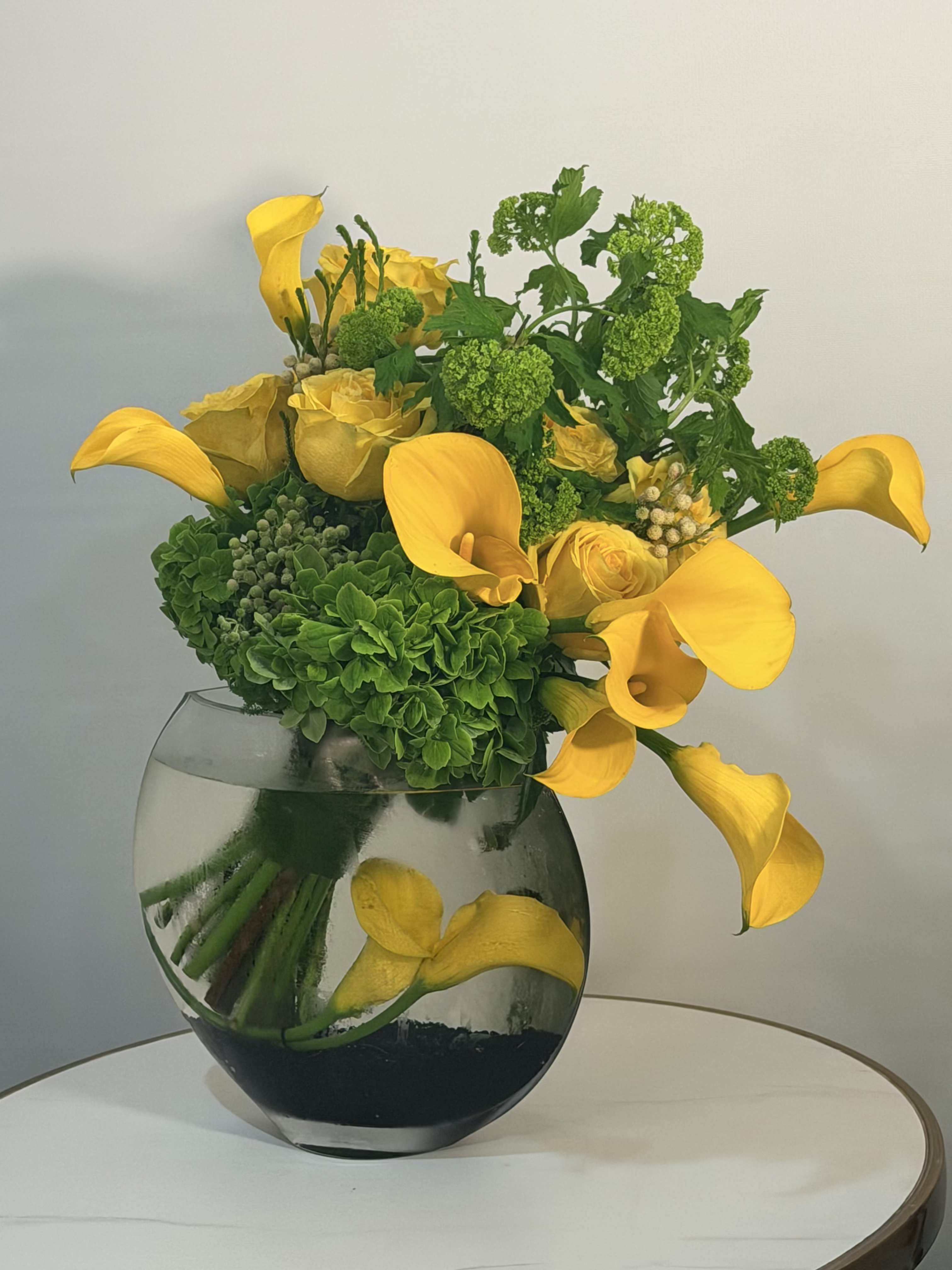 Golden Citrus Bloom - A vibrant and refreshing floral arrangement featuring elegant yellow calla lilies, premium yellow roses, and lush green hydrangea, beautifully designed in a modern glass vase. This arrangement brings a clean, radiant energy perfect for any occasion birthdays, celebrations, or simply to brighten someone’s day. Handcrafted with attention to detail, this design highlights a bold yellow palette balanced with rich green textures, creating a fresh and sophisticated look. We offer same day flower delivery across: Beverly Hills, Bel Air, West Hollywood, Beverly Grove, Studio City, Sherman Oaks, Encino, Hollywood, Hollywood Hills, Culver City, Santa Monica, Venice, Marina Del Rey, Topanga, and surrounding areas. Order today and enjoy fast, reliable same day flower delivery with premium quality and stunning presentation.