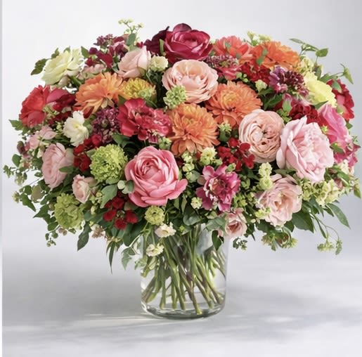 Thats the one! - A vibrant celebration of color and movement, this lush arrangement is designed to captivate from every angle. Featuring an artful blend of garden roses, ranunculus, dahlias, and seasonal blooms in rich shades of coral, blush, crimson, and soft green, it evokes the warmth and energy of a perfectly curated gathering.  Composed in a clear glass vessel to showcase the natural beauty of each stem, this piece balances abundance with intention—layered textures, tonal depth, and an organic, garden-inspired silhouette create a look that feels both elevated and effortlessly alive.  Perfect for statement gifting, celebrations, or bringing life into a space, this design is for those who appreciate bold beauty with a refined touch.  Details: • Premium seasonal blooms in coral, blush, red, and fresh green • Designed in a clear glass vase for a natural, airy presentation • Lush, multidimensional composition with a garden-style finish  A striking expression of joy, artistry, and modern floral luxury.  *show in Deluxe