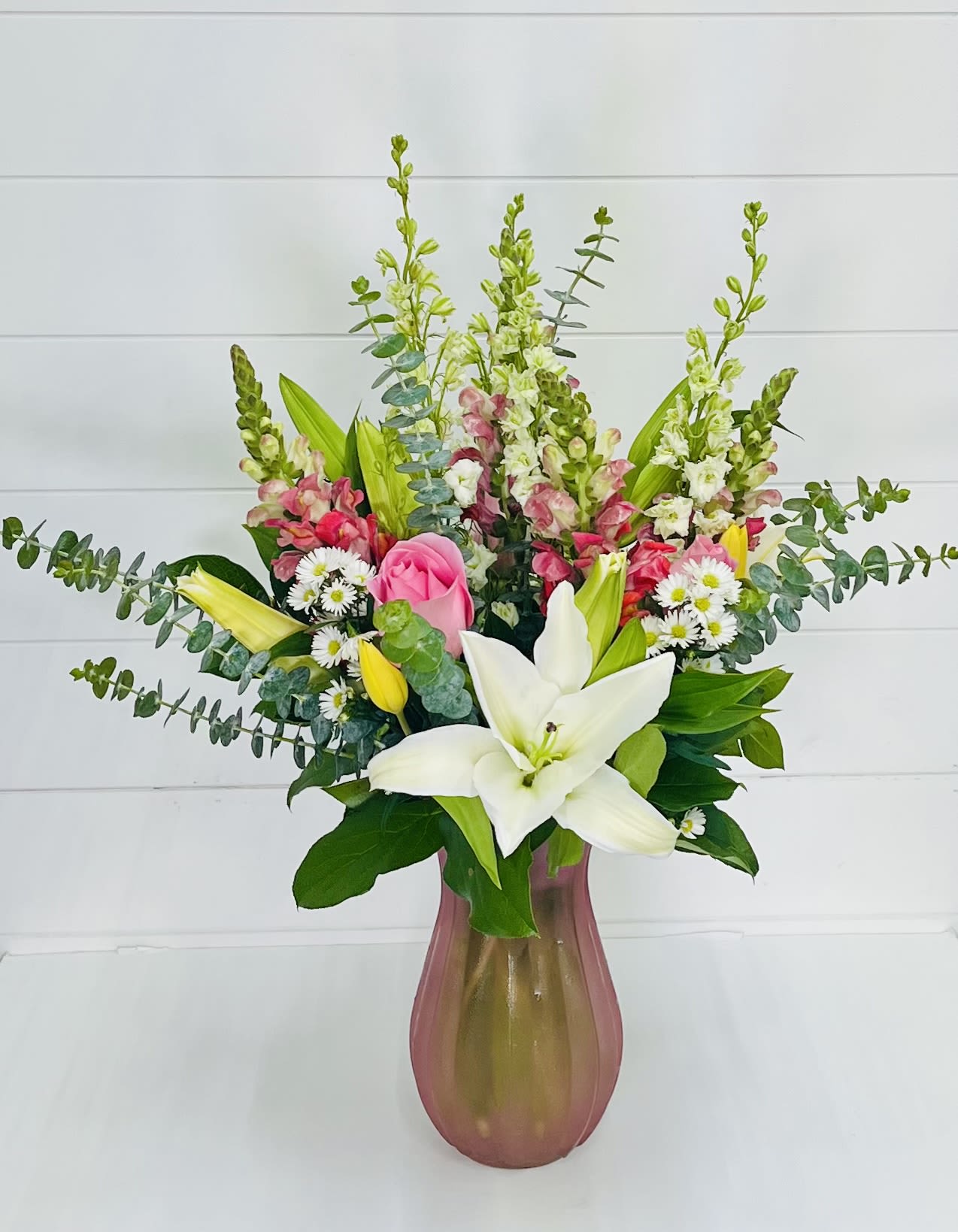 Sassy Lady - The Sassy Lady arrangement is a vibrant celebration of beauty, personality, and charm. Designed with a playful mix of yellow, pink, and white blooms, this bouquet features elegant snapdragons, graceful lilies, classic roses, cheerful daisies, fresh tulips, and lush greenery.  Full of color and confidence, Sassy Lady is perfect for brightening someone’s day, celebrating a special moment, or treating a mom who deserves something as bold and beautiful as she is. This arrangement brings together soft elegance and a touch of sass—making it truly unforgettable.  Perfect for: Mother’s Day, birthdays, celebrations, or just because.  Delivery Available In: Smyrna, Marietta, Mableton, Austell, and Atlanta.