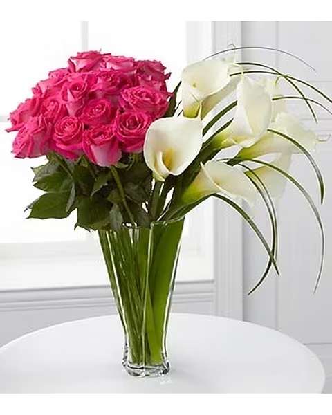 Irresistible Luxury Bouquet - Blooming with roses and open-cut calla lilies, this exquisite flower bouquet will bring wonder and elegant beauty into their every day. Brilliant fuchsia roses are arranged next to white open-cut calla lilies accented with lily grass glades for an impressive effect. Presented in a superior clear glass twist vase, this flower arrangement is a wonderful gift that will shower them with love and happiness. 