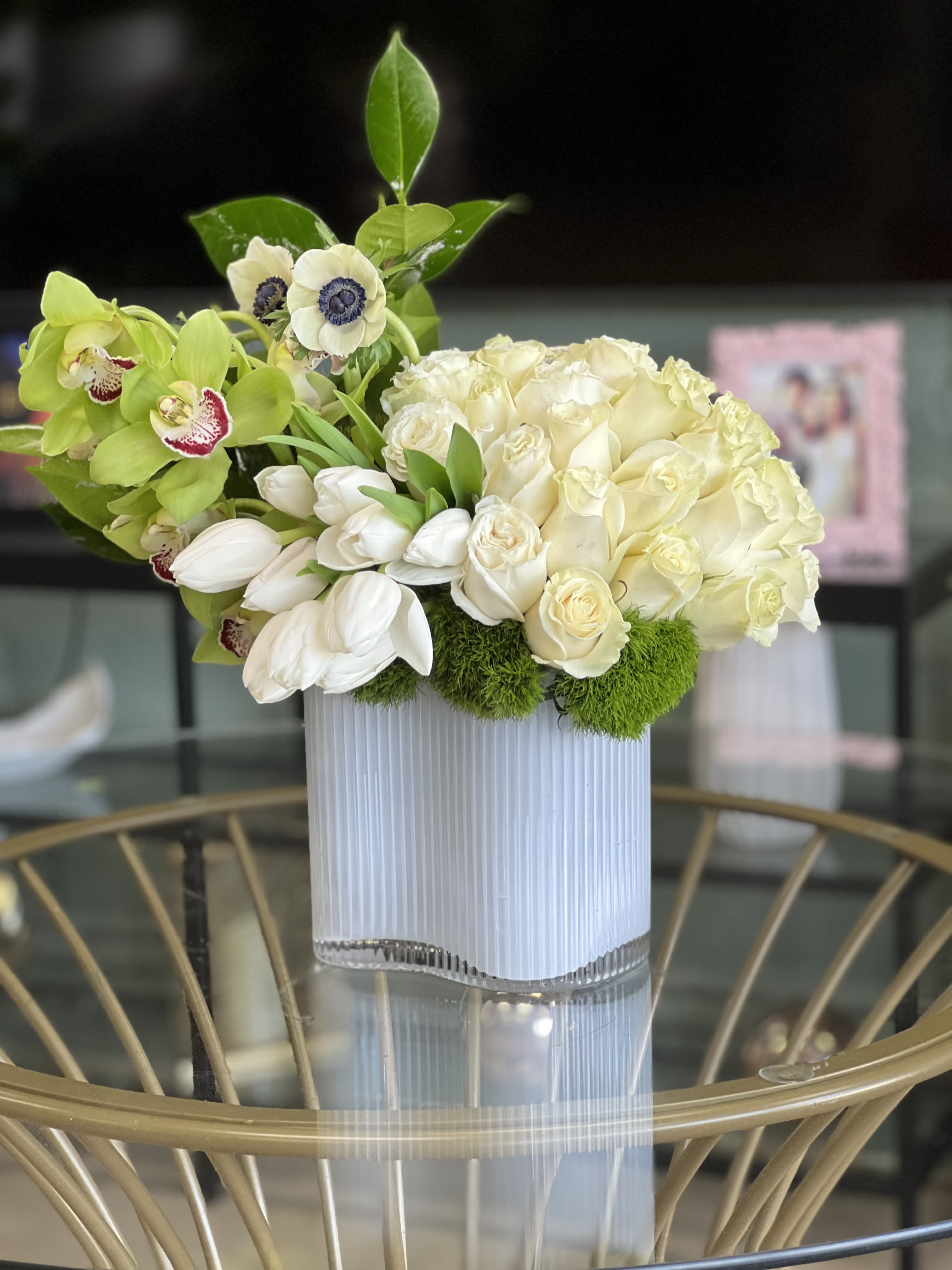 Del Mar - This gorgeous, fresh floral arrangement features white Roses, Tulips, and Anemones, offset with luscious green Cymbidium Orchids and soft green Dianthus