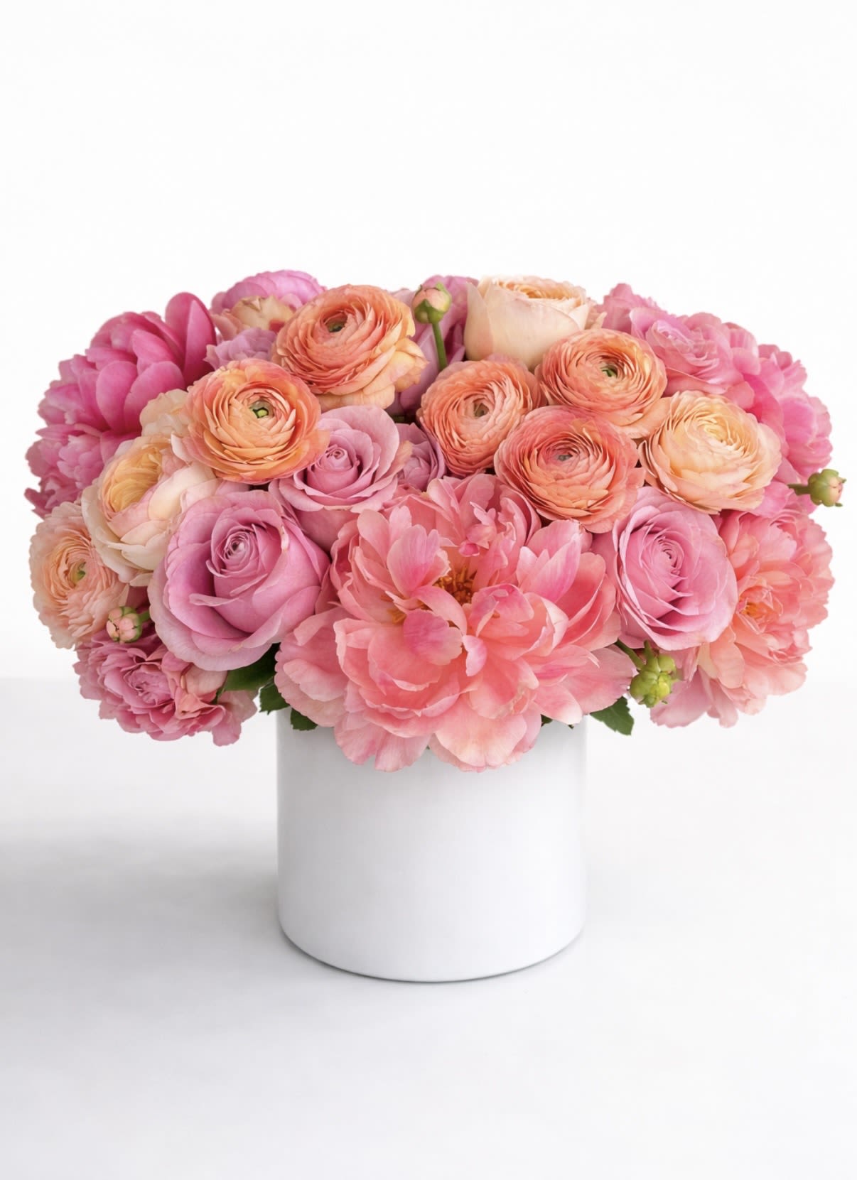 That good, good - An exquisite composition of blush, coral, and soft peach tones, this arrangement is a celebration of modern romance and effortless elegance. Featuring lush garden roses, delicately layered ranunculus, and full, ruffled peonies, each bloom is thoughtfully selected for its richness in texture and refined color story.  Designed in a clean, contemporary vessel, this piece offers a perfect balance of softness and structure—making it an ideal statement for intimate gatherings, elevated gifting, or a beautifully curated home.  Whether sent as a heartfelt Mother’s Day gesture or to mark a meaningful moment, this arrangement embodies warmth, beauty, and quiet luxury.  Details: • Premium seasonal blooms in blush, coral, and soft peach • Full, lush composition with a refined, garden-inspired aesthetic  A timeless expression of love, thoughtfully designed to leave a lasting impression. *shown in premium version