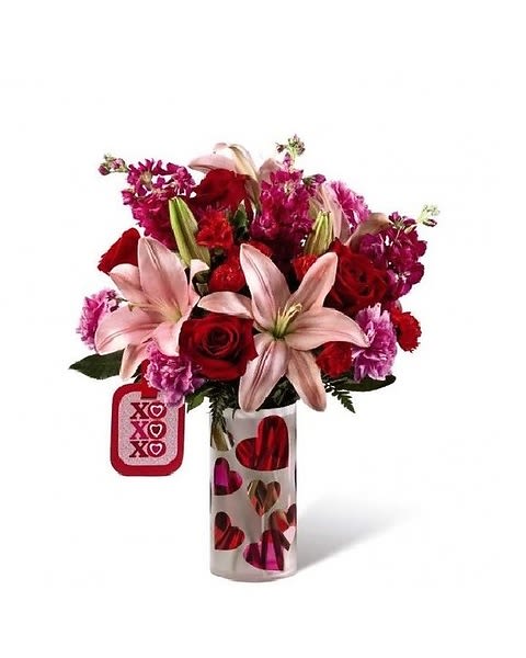 Love You XO - Love is in the air this Valentine's Day! The FTD® Love You XO™ Bouquet by Hallmark is the perfect way to celebrate the loves in your life, whether it be your sweetheart, a favorite family member, or your best friend. Pink Asiatic Lilies capture their attention with their large star-shaped blooms set against a blushing backdrop of red roses, red mini carnations, hot pink carnations, hot pink gilly flower and lush greens. Arranged with a loving hand within a keepsake frosted glass vase with a pink and red heart design throughout, this Valentine flower bouquet is presented with a Hallmark tag that reads, "Love You!" on one side and, "XO, XO, XO," on the other to create a beautiful way to celebrate love this coming February 14th. 