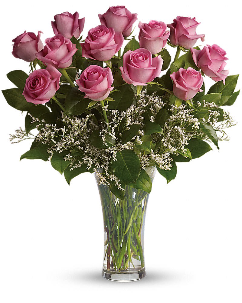 Long-stem pink roses with white filler flowers arranged in a clear glass vase