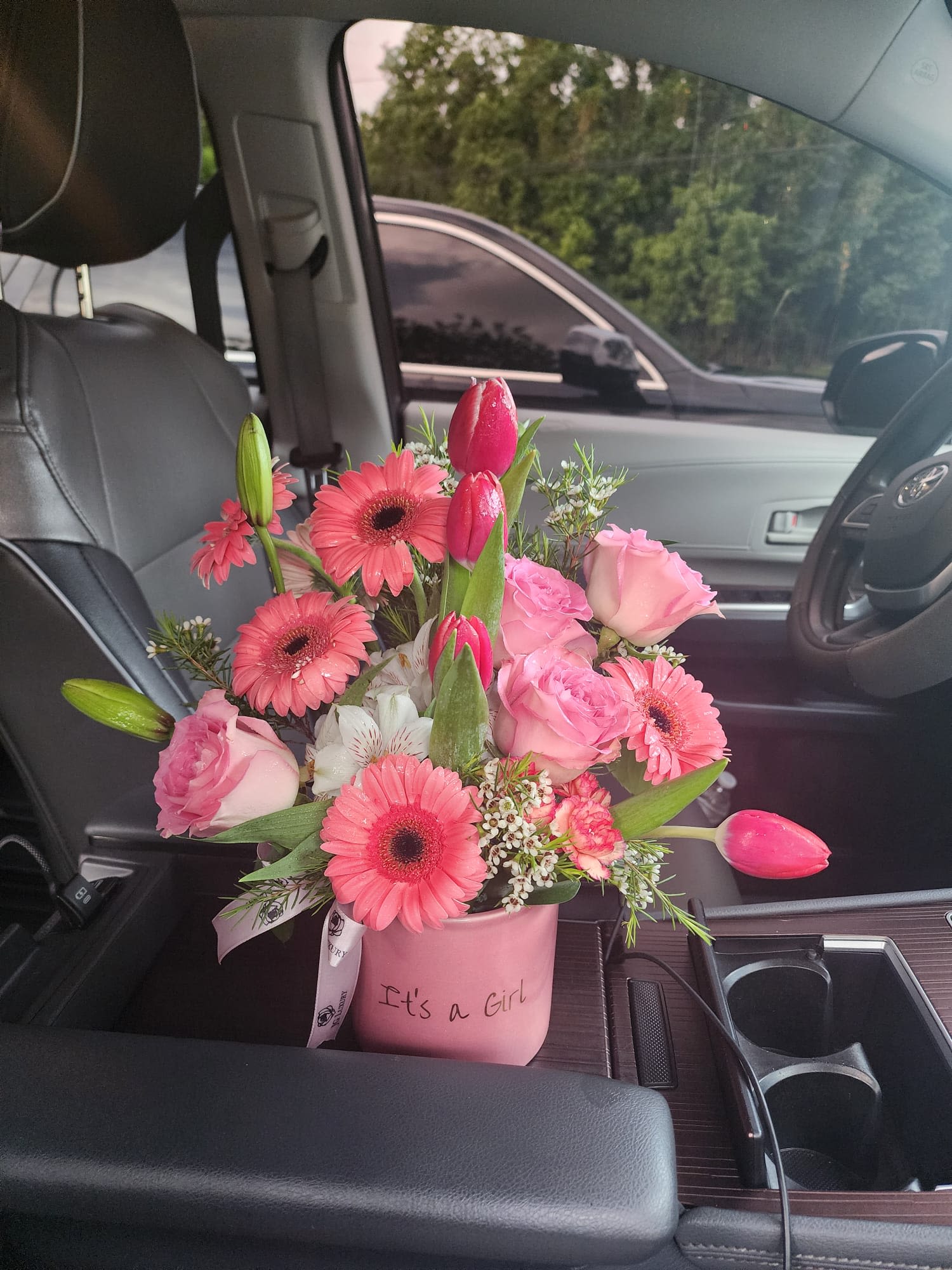 Pink 'It's a Girl' flower arrangement with tulips, gerbera daisies, and roses in a small container