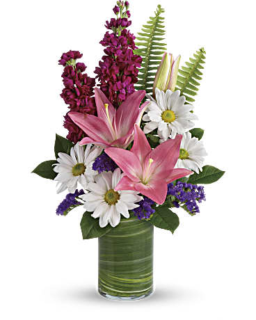 Pink lilies, white daisies, and purple flowers in a clear glass cylinder vase