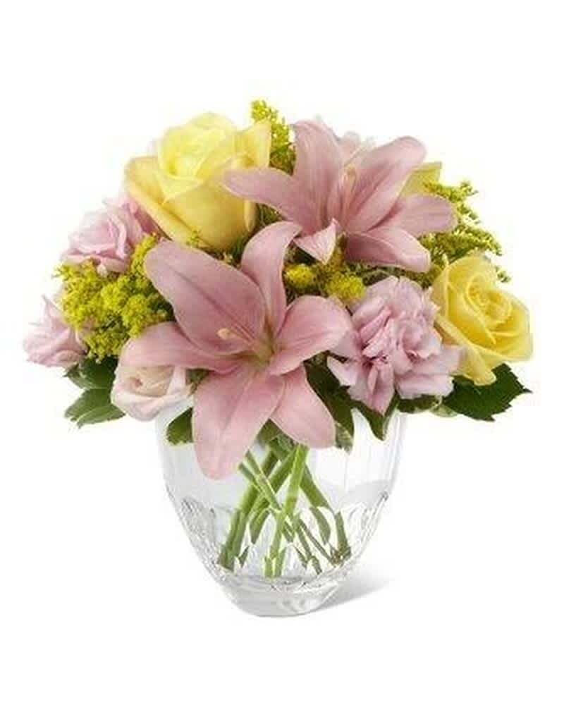 Pastel arrangement of pink lilies, yellow roses, and pink carnations in a clear glass vase