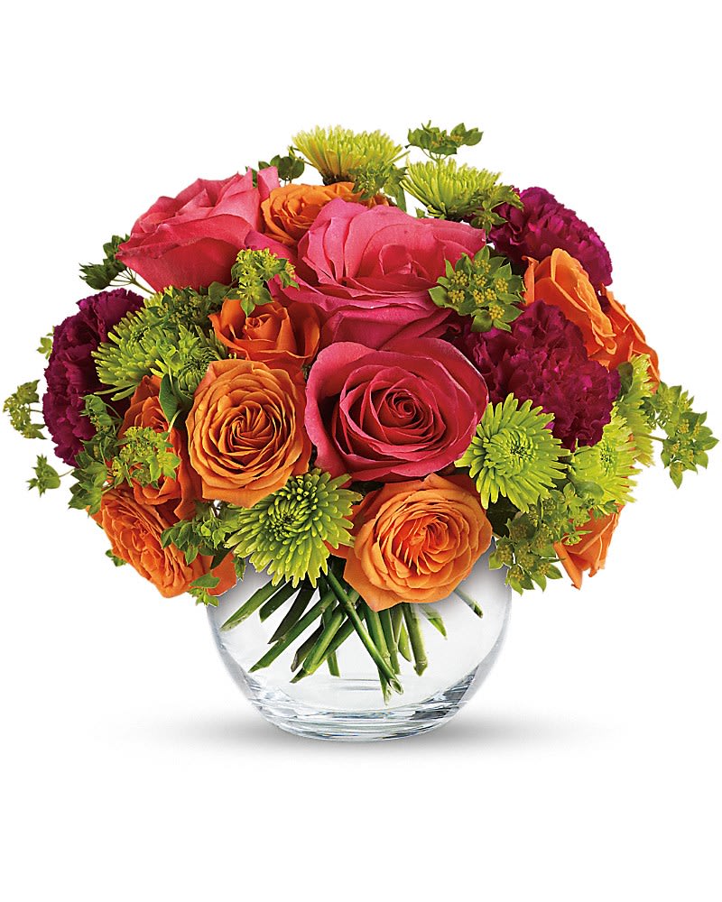 Round bouquet of pink and orange roses with green mums in a clear glass vase