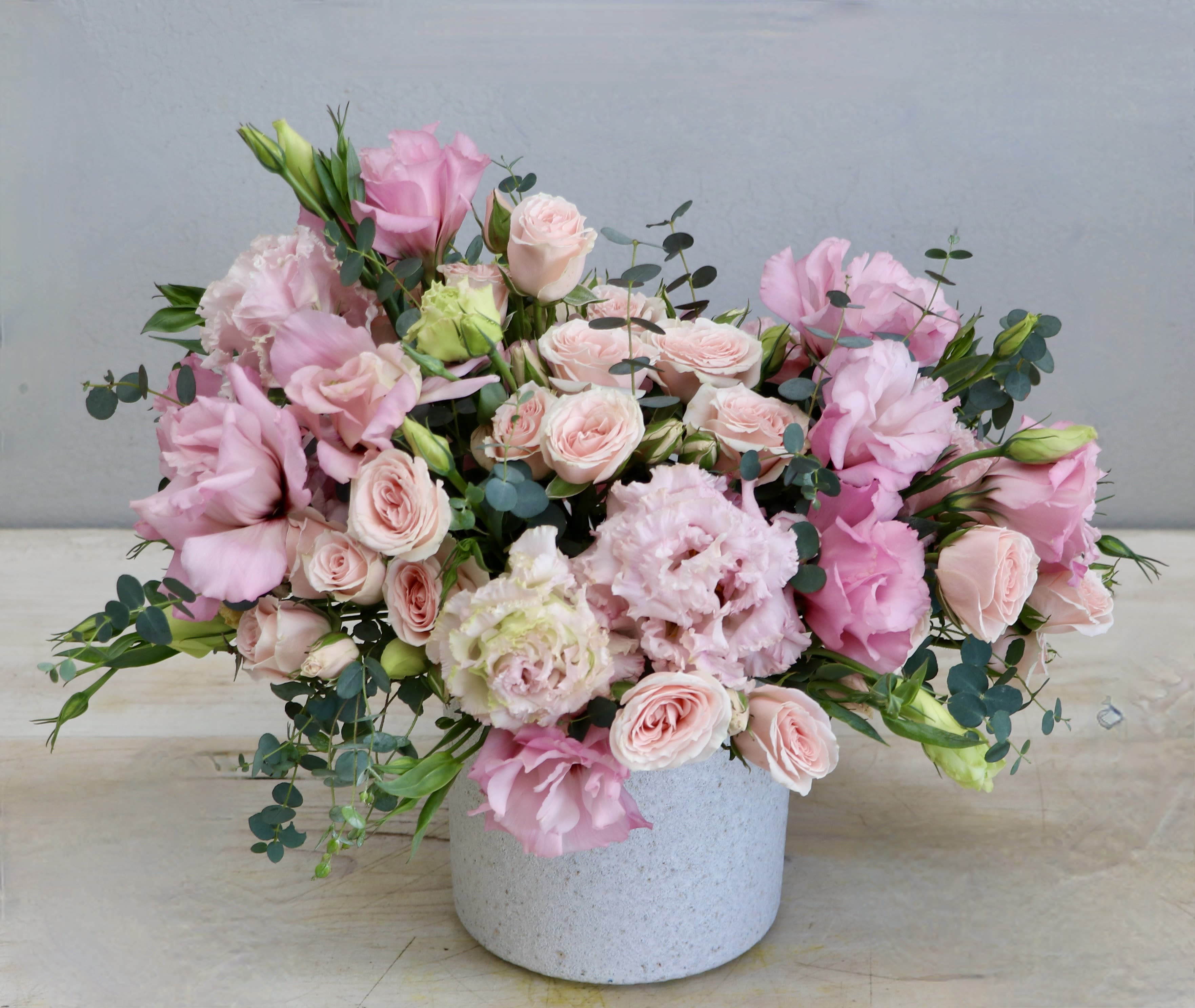 Low pink and blush flower arrangement in a white ceramic pot