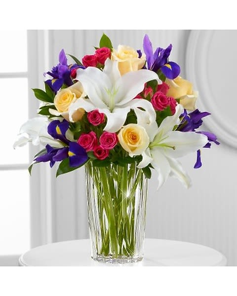 New Day Dawns - Exclusively for Vera Wang Flowers. The designer's inimitable style is brilliantly captured in this colorful, dramatic and stunningly modern arrangement set in an exclusive, ribbed, handcrafted glass vase. The arrangement combines vibrant iris, roses and spray roses and white lilies for an elegant display worthy of the world's most elegant designer. The vase can be substituted due to availability.  
