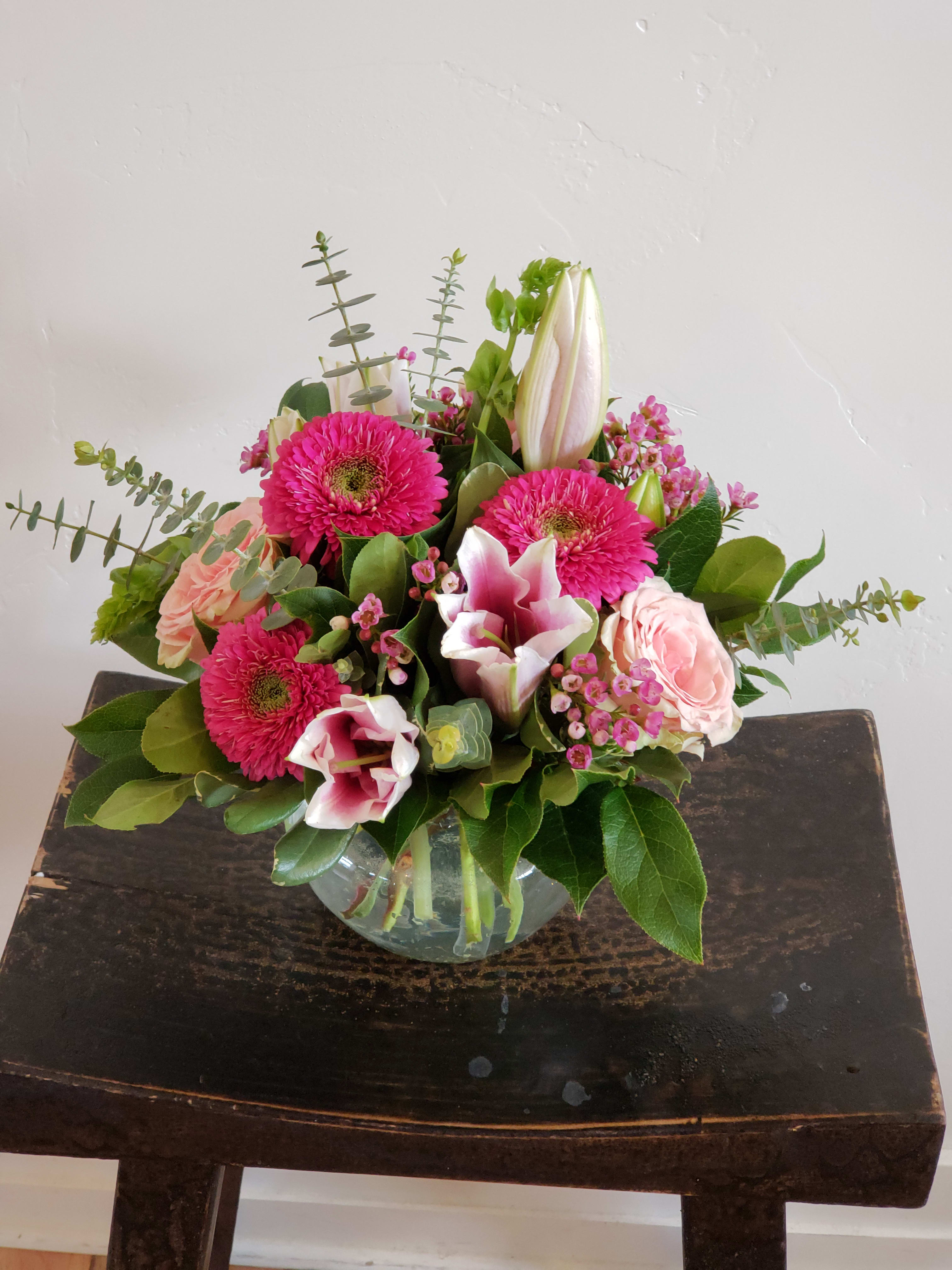 Bright pink and blush flower arrangement with lilies, gerbera daisies, and roses in a glass bowl vase