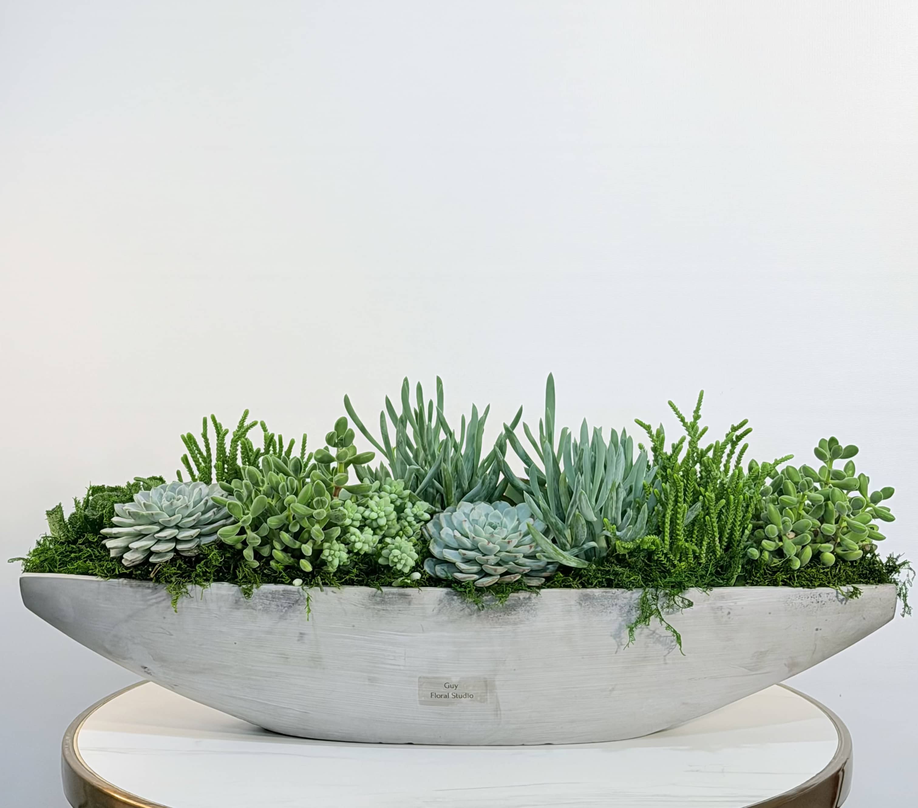 Desert Harmony Garden - A stunning modern succulent arrangement designed to bring natural balance and sculptural beauty into any space. The Desert Harmony Garden features a curated mix of premium succulents, including echeveria and textured greenery, arranged in a sleek, elongated ceramic vessel for a clean and contemporary look. This low maintenance design is perfect for homes, offices, or as a unique and long lasting gift. Its wide, horizontal style makes it an ideal centerpiece for dining tables, consoles, or reception areas. Approximate size: Width 26 inches, Height 11 inches. Available for same day delivery, carefully arranged and presented with attention to detail. We proudly offer same day plant and flower delivery to: Beverly Hills, Bel Air, West Hollywood, Beverly Grove, Studio City, Sherman Oaks, Encino, Santa Monica, Hollywood, Hollywood Hills, Culver City, Venice, Marina Del Rey, Malibu, Topanga and surrounding areas. Perfect for housewarming gifts, corporate gifting, or anyone who appreciates modern greenery with a refined aesthetic. 