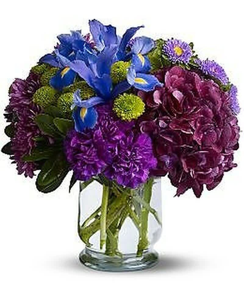 Compact purple and blue mixed flower arrangement in a clear glass cylinder vase