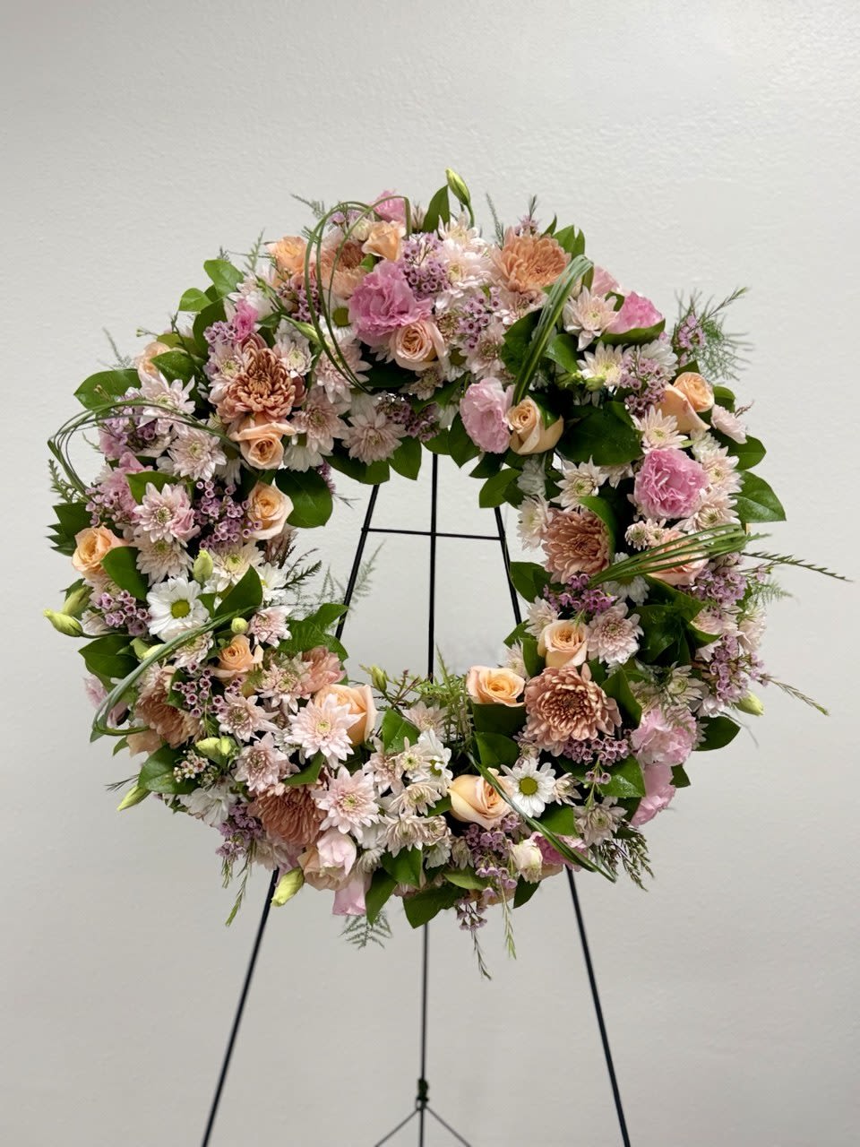 Lasting Serenity Pastel - A beautiful white and green tribute wreath that calms, this easel arrangement celebrates a full life and a peaceful passing. The size of the foam is 20" and the height of the easel is 60".