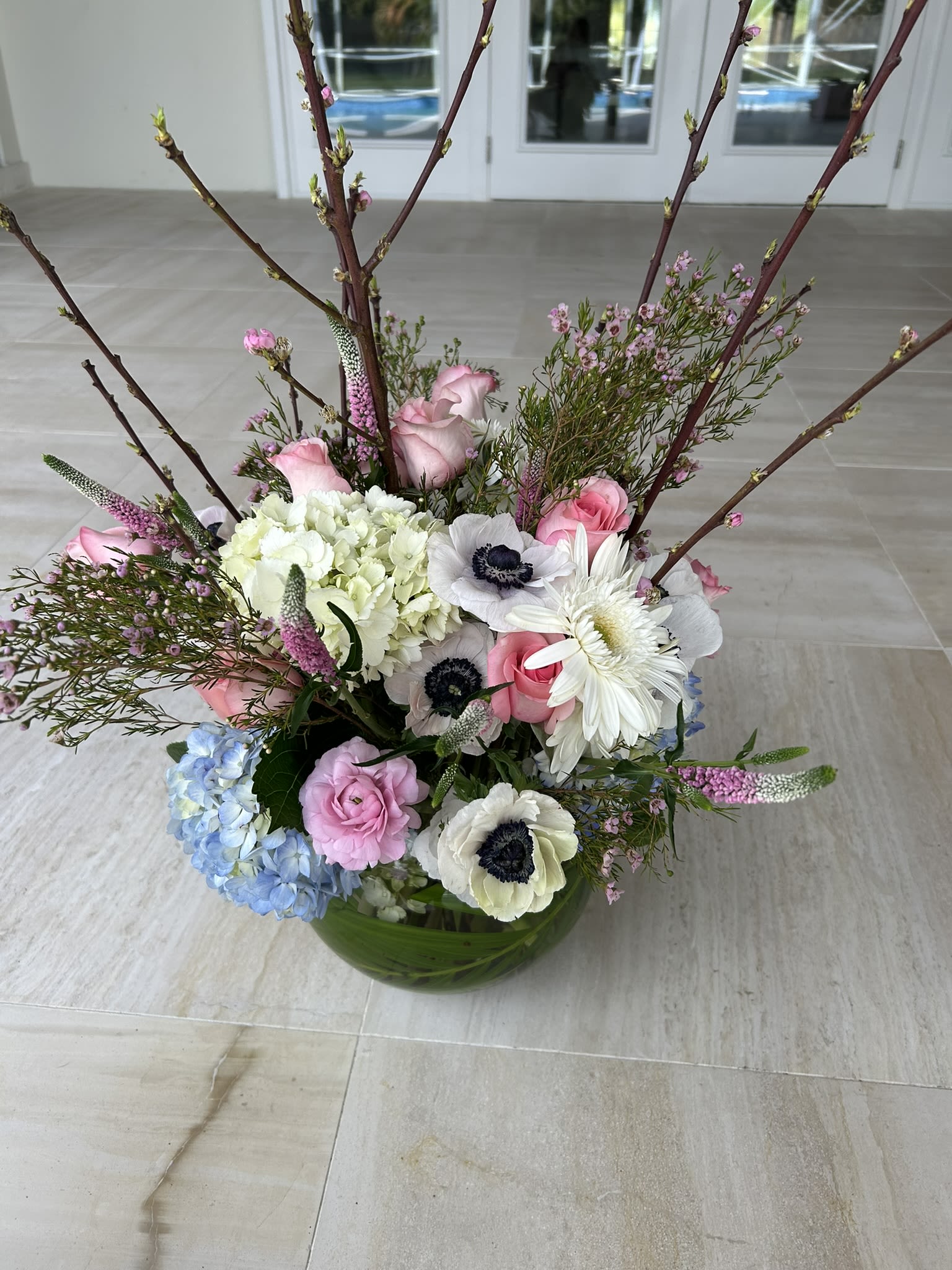 As beautiful as you - A generously filled bowl of seasonal flowers, including Hydrangeas, Peony, Roses, Anemone, Veronica, Gerber, accented with pink was flower and brought to life with out standing Blossoming cherry blossom branches ,branches available mainly in spring months