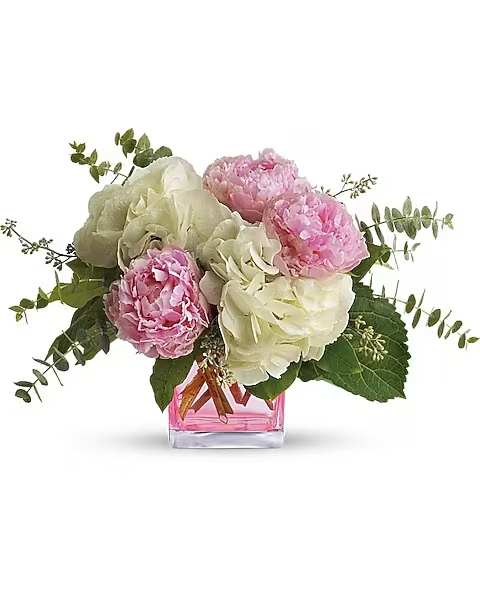 Teleflora's Pretty in Peony - These pretty pink peonies must feel like they've landed in paradise. And perhaps they have, joined as they are by dazzling hydrangea blooms and greens. Big beautiful pink peony blossoms, brilliant white hydrangea and two kinds of eucalyptus are perfectly arranged in a distinctive keepsake cube. It's no wonder so many people believe that the prettiest pink is peony pink.   