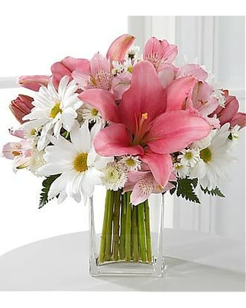 Pink lilies and white daisies arranged in a clear rectangular glass vase