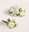 Boutonniere - A compact white boutonniere and matching corsage set crafted for classic elegance-perfect for weddings, proms, or any formal occasion where the person you're honoring should look polished and timeless. The boutonniere centers on a single white rose bloom with delicate white filler flowers and fresh green accents, so he'll feel quietly distinguished and put together beside the rest of the party.  Carefully bound with coordinating ribbon, the pieces are small, formal, and easy to pin to a lapel or sash without overpowering the outfit. The soft white palette and neat construction make this set a versatile choice for brides, grooms, attendants, or guests; order with your event date in mind and store in a cool place until delivery to keep blooms looking their best.