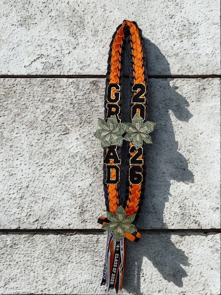 Graduation Lay - Make their graduation moment unmistakable with a braided ribbon lei in bold orange and black-perfect as a graduation accessory or ceremony keepsake. This graduation lay (braided ribbon lei) reads "GRAD 2026" in bold black letters with gold trim, so the person you're honoring will look and feel celebrated the moment they step across the stage.  Hand-braided satin ribbons form two parallel strands in orange and black, accented with folded currency rosettes and origami-style money flowers for texture and sparkle. Printed graduation ribbons, hanging ribbon streamers in coordinating school colors, and fabric letter and number patches create a layered, festive look; a small tassel of narrow ribbons finishes the bottom for movement as they walk. The lei is designed to be worn comfortably around the neck and to pair with caps and gowns for commencement photos.  Give this to a grad to mark academic achievement, cap-and-gown ceremonies, or senior celebrations-she'll feel recognized and spirited the whole day. The durable satin braid and secured accents mean it wears well during processions and photos; order with any special delivery timing needed for the ceremony.