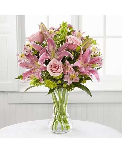Beauty &amp; Grace - Extend warm wishes for an exquisite spring with this majestic bouquet of blushing blooms. Pale pink roses, Peruvian lilies and Oriental lily stems combine with the vibrant green Bells of Ireland to create an arrangement displaying Spring's splendid beauty. Paired with a hand blown designer clear glass vase, this bouquet is a gift of grace that will delight your special recipient. 
