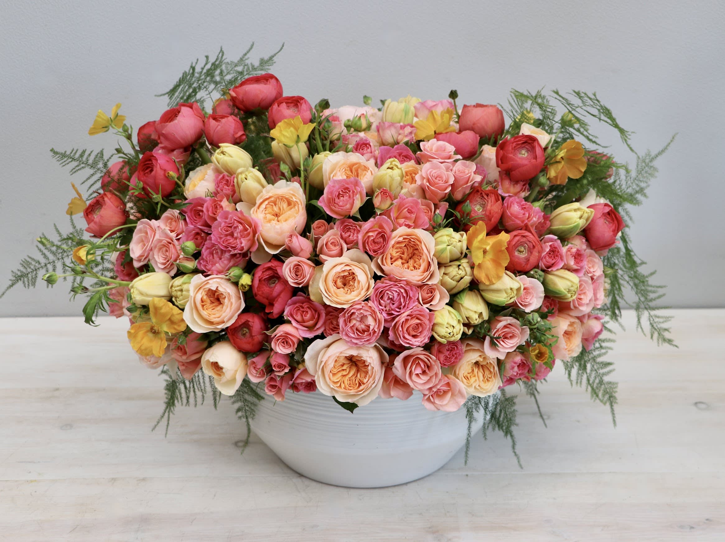Shades Of Spring - WeHo - For this grand arrangement we've paired together some of our favorite blooms. This arrangement includes ranunculus, garden roses, tulips, and seasonal greenery in a white ceramic vase. The photo shown is in the standard size and stands at approximately 2ft tall and wide, to get more blooms please be sure to upgrade! 