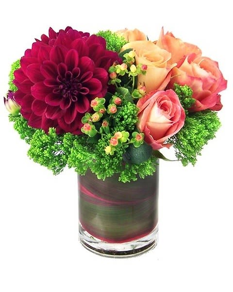 Brighten Up Your Day - A palette of classic peaches, greens, and berries are artistically arranged in a cylindrical vase and garnished with a tropical leaf wrap.